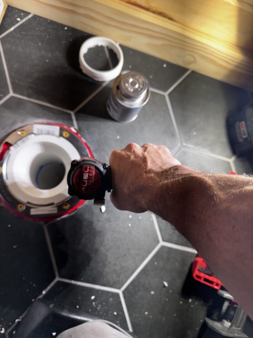 A person pouring coffee from a French press into a cup on a tiled floor.