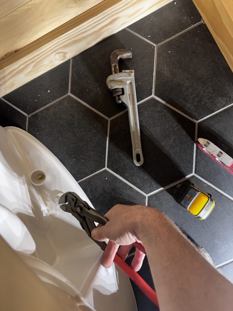 Person using a wrench to fix a bathroom sink.